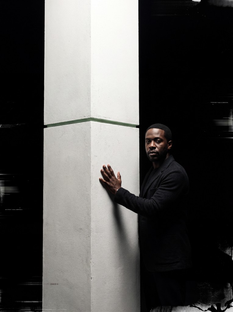 A person steadying a load-bearing column, standing at the edge of the light.